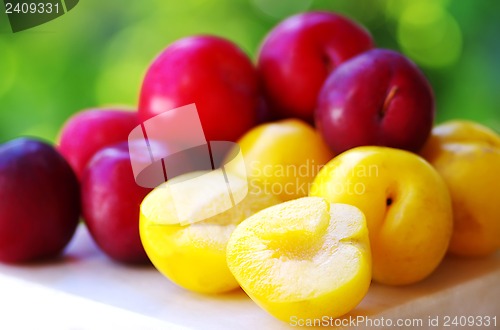 Image of Ripe plums on wooden table and sliced plum