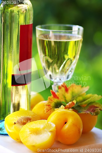 Image of White wine bottle, glass and plums