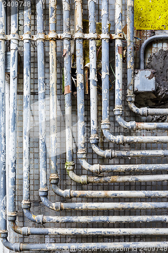 Image of Series of parallel old pipes on wall