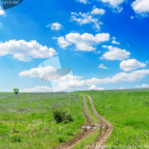 Image of winding road in green grass and cloudy sky