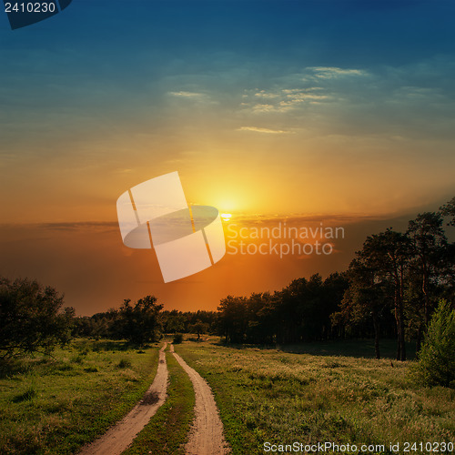 Image of dramatic sunset over road in wood