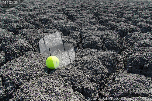 Image of tennis ball on cracked land