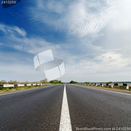 Image of road closeup under cloudy blue sky
