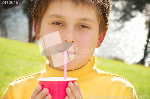 Image of Young boy drinking strawberry milk outdoors