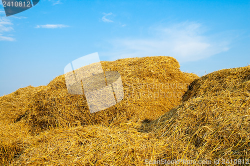 Image of stack of straw on a background blue sky with clouds