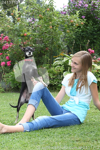 Image of Cute little dog playing with a young girl