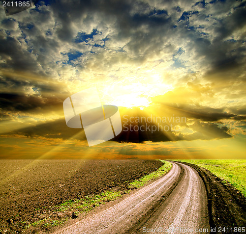 Image of sun and clouds over field with road
