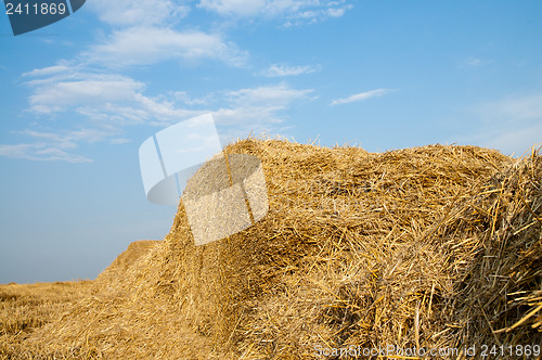 Image of stack of straw on a background blue sky with clouds