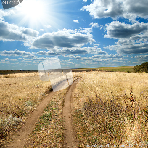 Image of sun and clouds over rural road