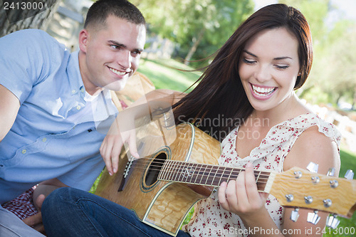 Image of Mixed Race Couple at the Park Playing Guitar and Singing