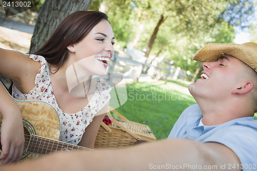 Image of Mixed Race Couple with Guitar and Cowboy Hat in Park