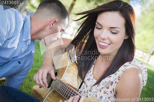 Image of Mixed Race Couple at the Park Playing Guitar and Singing