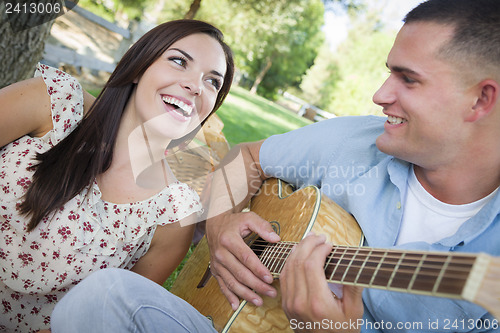 Image of Mixed Race Couple at the Park Playing Guitar and Singing