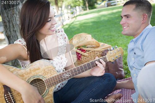 Image of Mixed Race Couple at the Park Playing Guitar and Singing