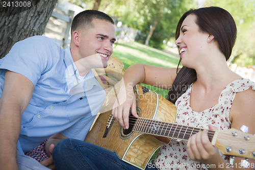 Image of Mixed Race Couple at the Park Playing Guitar and Singing