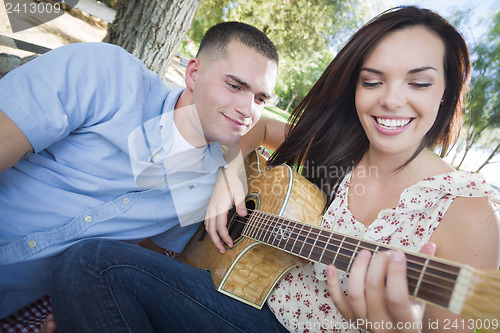 Image of Mixed Race Couple at the Park Playing Guitar and Singing