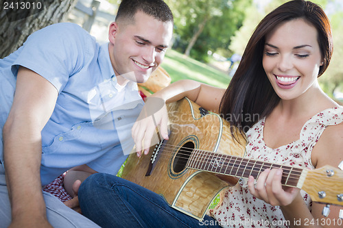 Image of Mixed Race Couple at the Park Playing Guitar and Singing