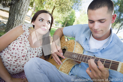 Image of Mixed Race Couple at the Park Playing Guitar and Singing