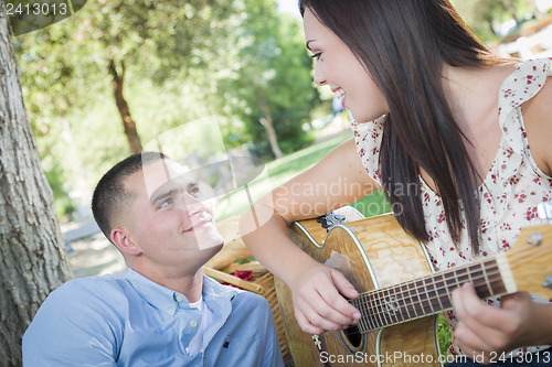 Image of Mixed Race Couple at the Park Playing Guitar and Singing