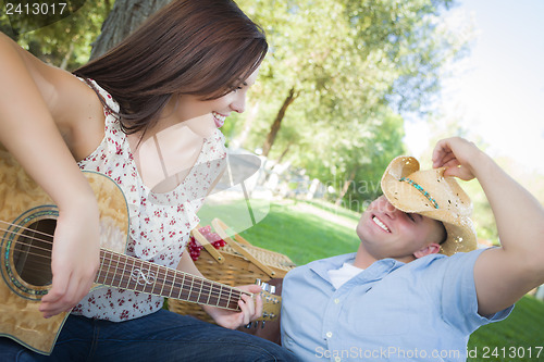 Image of Mixed Race Couple with Guitar and Cowboy Hat in Park