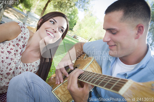 Image of Mixed Race Couple at the Park Playing Guitar and Singing