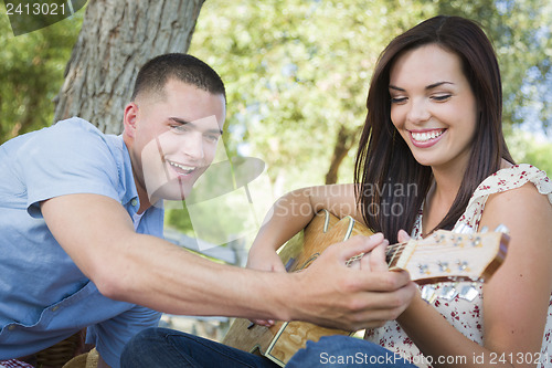 Image of Handsome Young Man Teaching Mixed Race Girl to Play Guitar