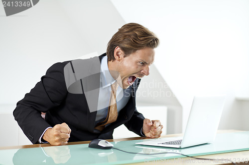 Image of Frustrated businessman shouting at laptop