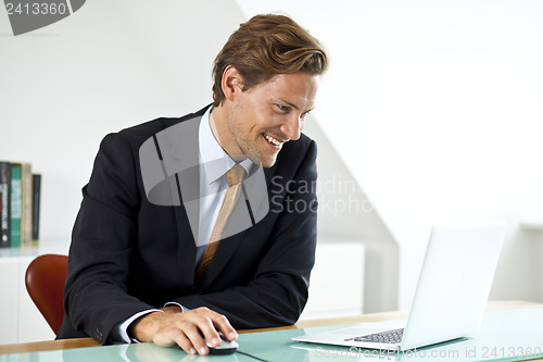 Image of miling handsome businessman using laptop in office