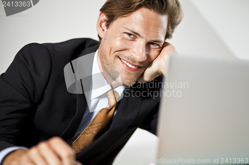 Image of Smiling Caucasian businessman using laptop