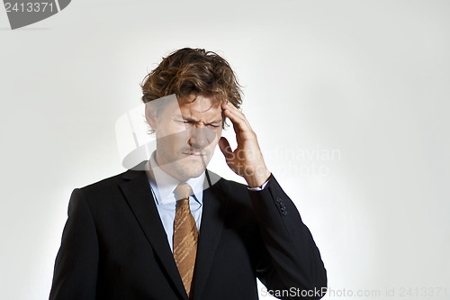 Image of Aching businessman grabbing his head in pain