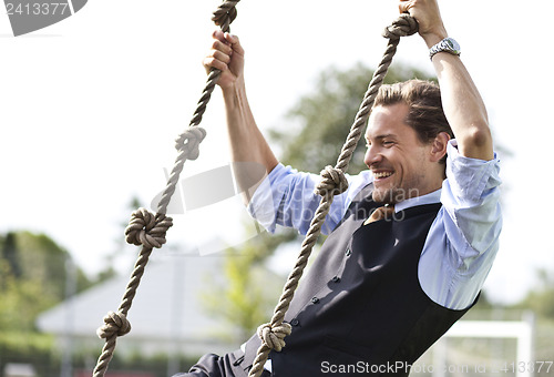 Image of Happy businessman playing, swinging in ropes