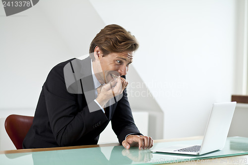 Image of Anxious businessman looking at laptop