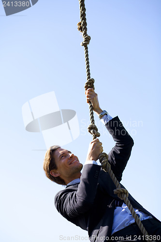 Image of Businessman climbing rope