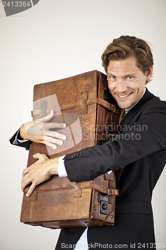 Image of Young businessman embracing his old suitcase