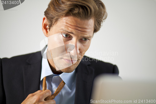 Image of Stressed businessman working on laptop