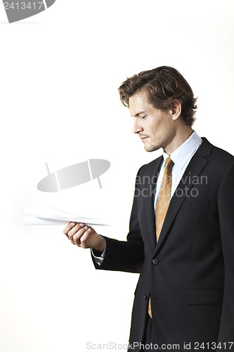 Image of Skeptical businessman looking at paper airplane