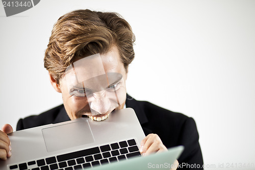 Image of Man biting a laptop in frustration