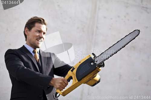 Image of Angry businessman wielding a chainsaw.