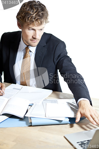 Image of Businessman reaching for laptop at work