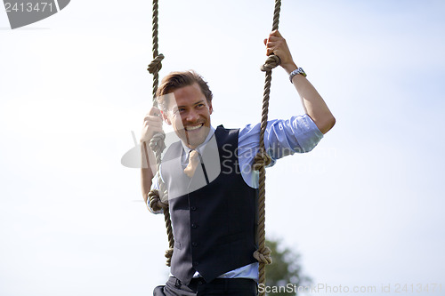 Image of Smiling businessman swinging in ropes