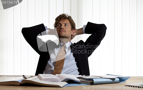 Image of Wondering businessman leaning back in his chair