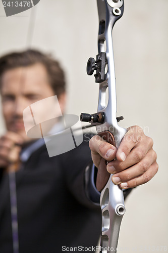 Image of Determined businessman aiming bow