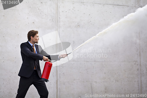 Image of Focused businessman using a fire extinguisher