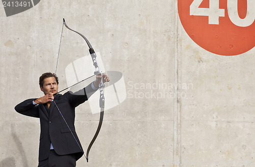 Image of Businessman aiming bow and arrow at target