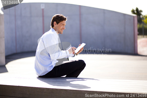 Image of Relaxed businessman holding tablet