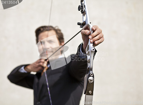 Image of Smiling businessman aiming bow