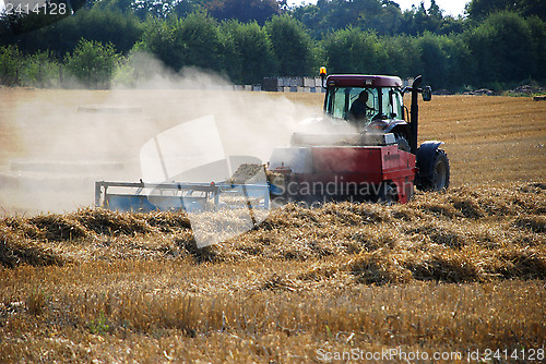 Image of Tractor baling straw in a field