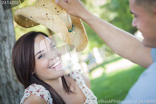 Image of Mixed Race Romantic Couple with Cowboy Hat Flirting in Park