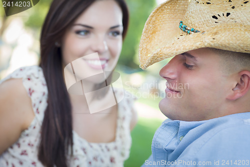 Image of Mixed Race Romantic Couple with Cowboy Hat Flirting in Park