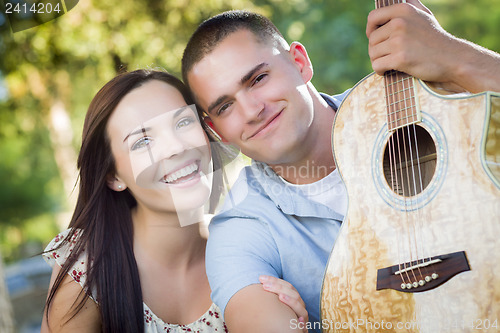 Image of Mixed Race Couple Portrait with Guitar in Park
